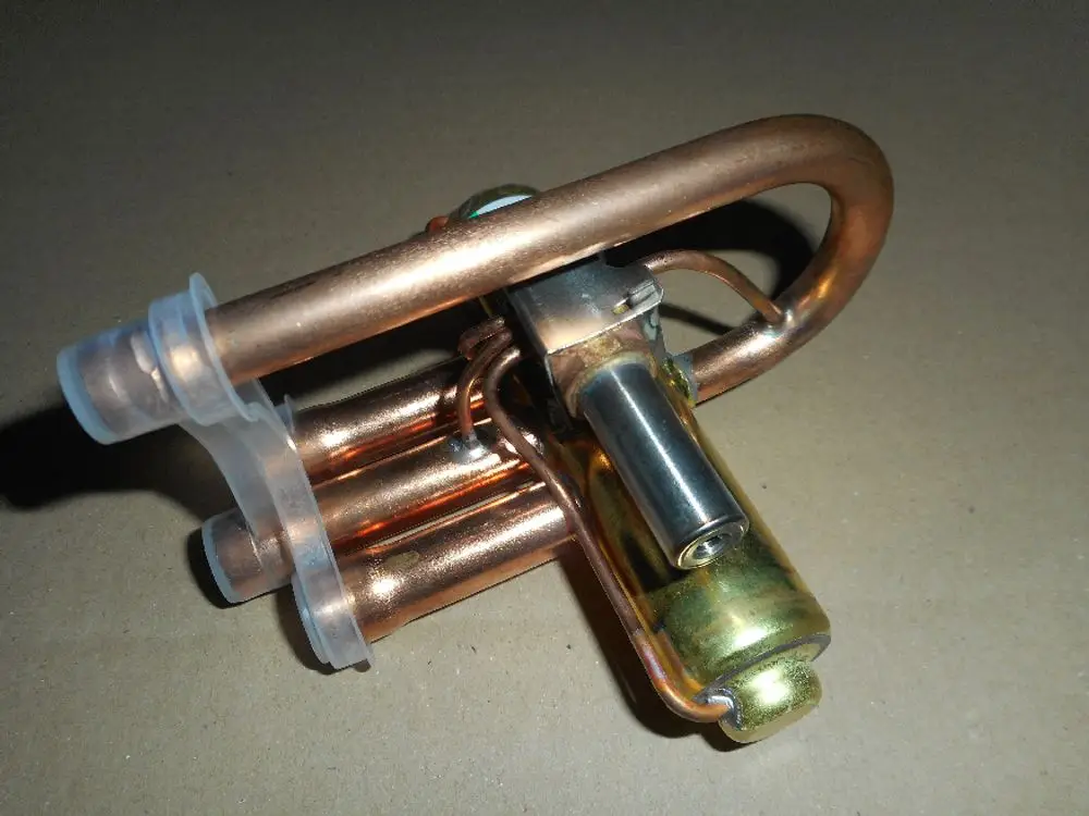 4-Wege-Umschalt-Ventil von Remeha mit Kupferrohren und einem mechanischen Betätigungsmechanismus, geeignet für Heizungsanlagen.